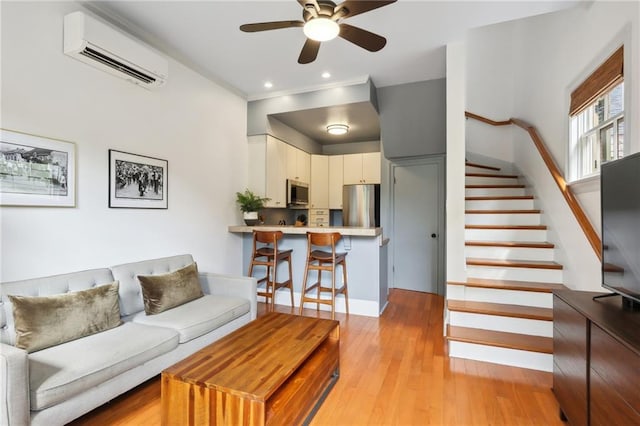 living room featuring ceiling fan, light wood-type flooring, and a wall mounted AC