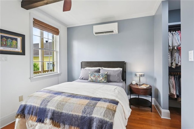 bedroom featuring ceiling fan, an AC wall unit, crown molding, hardwood / wood-style floors, and a closet