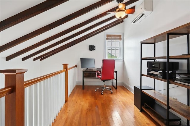 home office featuring a wall unit AC, ceiling fan, lofted ceiling with beams, and light hardwood / wood-style floors