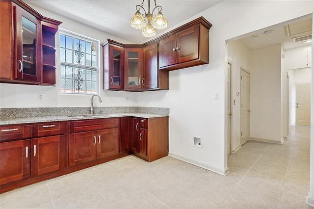 kitchen featuring light stone counters, decorative light fixtures, and sink