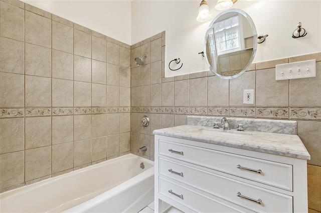 bathroom with tile walls, vanity, and tiled shower / bath