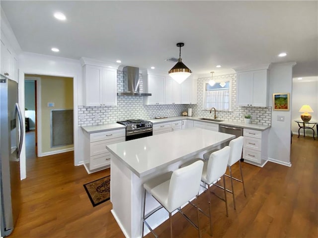 kitchen featuring stainless steel appliances, light countertops, white cabinets, a sink, and wall chimney range hood