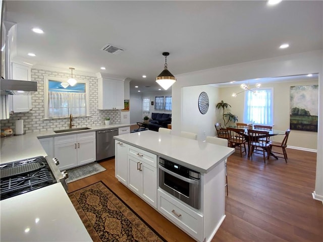 kitchen featuring appliances with stainless steel finishes, light countertops, a sink, and white cabinetry