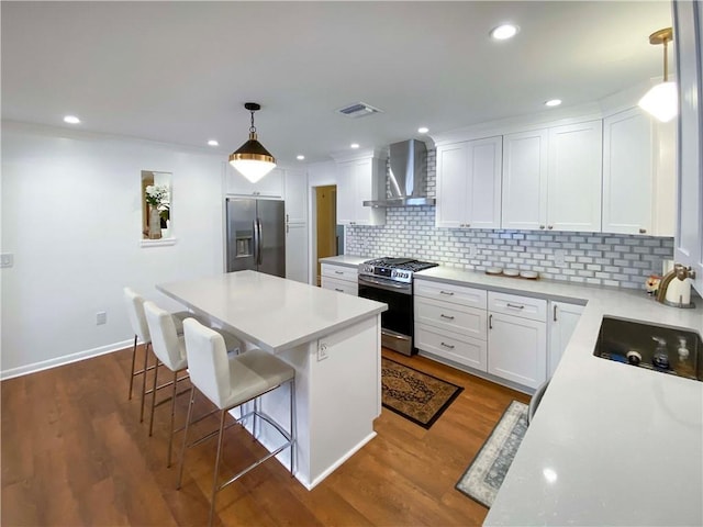 kitchen featuring stainless steel appliances, white cabinets, light countertops, and wall chimney exhaust hood