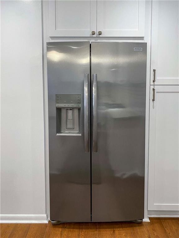 kitchen with light wood-style floors, white cabinets, stainless steel refrigerator with ice dispenser, and baseboards