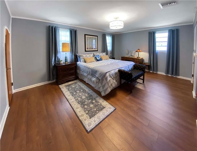 bedroom featuring baseboards, dark wood-style flooring, visible vents, and crown molding