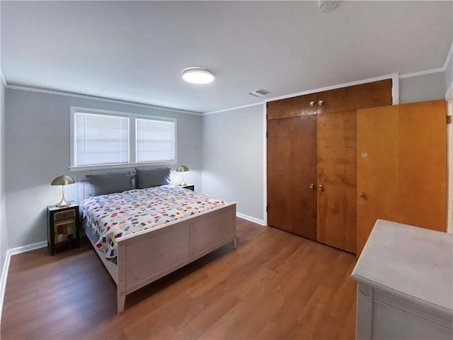 bedroom with crown molding, a closet, visible vents, and dark wood-type flooring