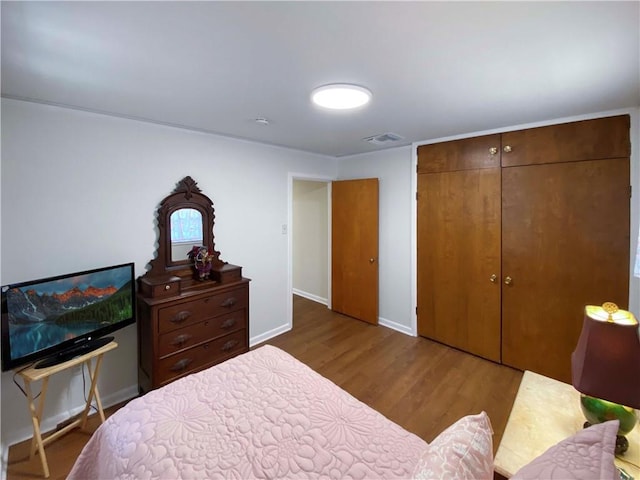 bedroom featuring dark wood-style floors, a closet, visible vents, and baseboards