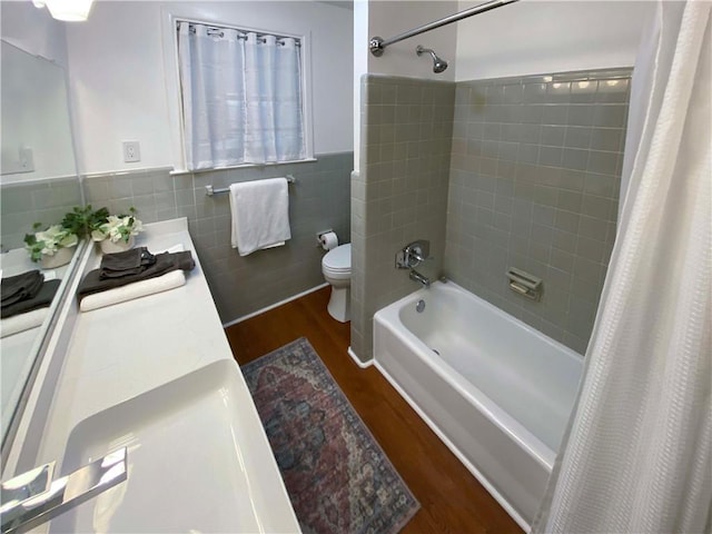 full bathroom with shower / bath combo, toilet, a wainscoted wall, wood finished floors, and tile walls