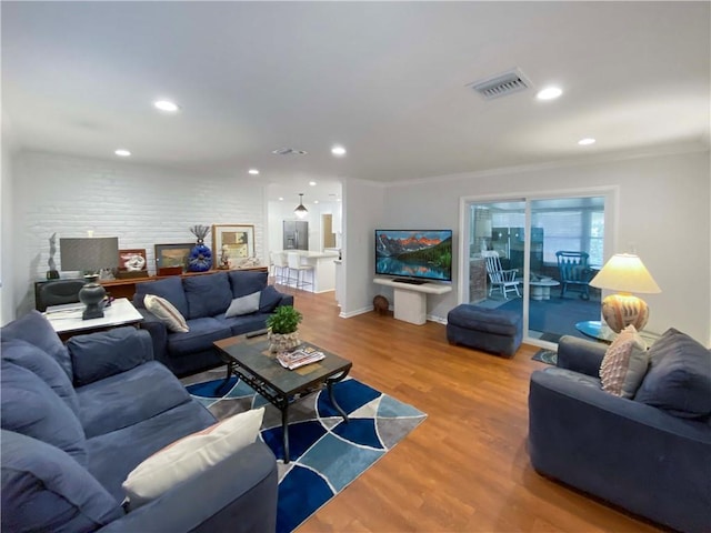 living room with ornamental molding, recessed lighting, visible vents, and wood finished floors