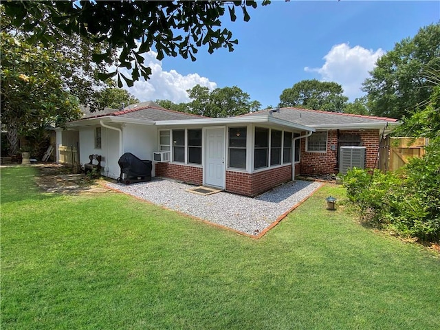 rear view of property featuring brick siding, a lawn, fence, and a sunroom