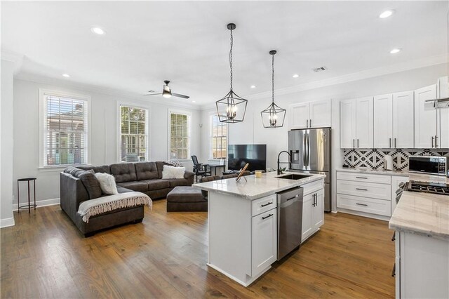 kitchen with a center island with sink, stainless steel appliances, white cabinets, hardwood / wood-style floors, and tasteful backsplash