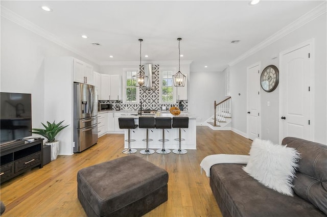 living room with a notable chandelier, ornamental molding, and light hardwood / wood-style floors