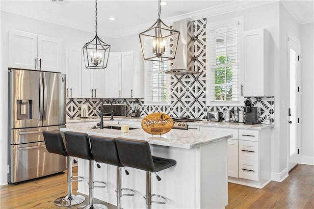 kitchen with light stone counters, backsplash, white cabinetry, stainless steel fridge, and crown molding