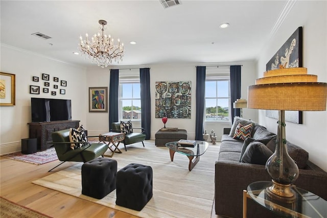 living room with an inviting chandelier, ornamental molding, and light wood-type flooring