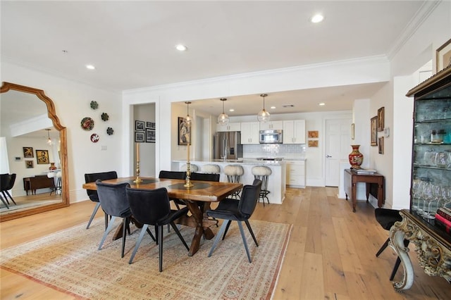 dining area featuring ornamental molding and light hardwood / wood-style flooring