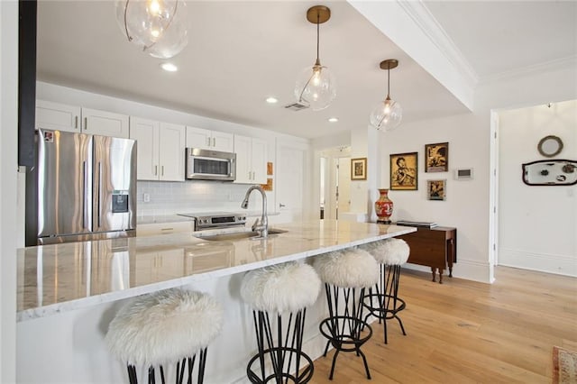 kitchen featuring white cabinetry, light stone counters, hanging light fixtures, a kitchen breakfast bar, and stainless steel appliances