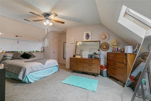 carpeted bedroom with ceiling fan, a textured ceiling, and lofted ceiling with skylight