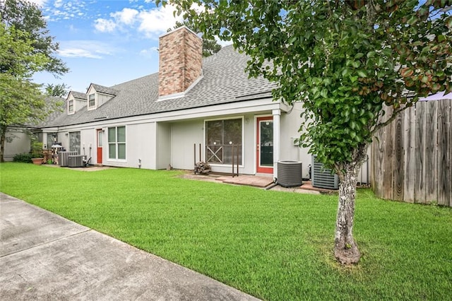 rear view of property with central air condition unit and a lawn