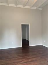 spare room featuring beam ceiling and dark hardwood / wood-style flooring