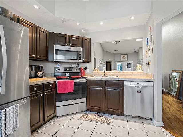 kitchen with dark brown cabinets, light wood-type flooring, sink, and appliances with stainless steel finishes