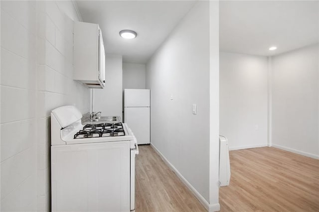 kitchen with light wood-type flooring, white appliances, sink, and white cabinets