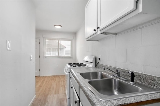 kitchen featuring sink, stainless steel gas stove, light hardwood / wood-style floors, and white cabinetry