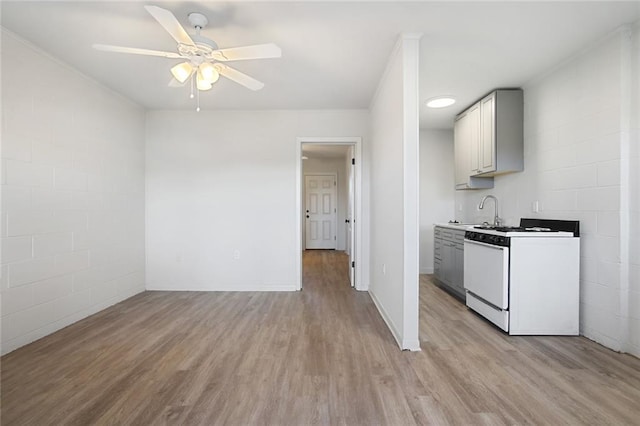 kitchen with light hardwood / wood-style floors, sink, white cabinets, white range with gas stovetop, and ceiling fan