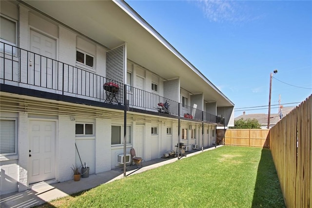 back of house featuring a lawn and a balcony