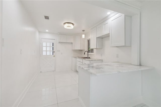 kitchen featuring kitchen peninsula, light stone counters, sink, white cabinets, and light tile patterned flooring