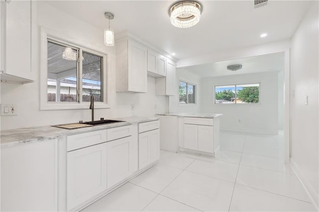 kitchen with white cabinetry, sink, light stone counters, pendant lighting, and light tile patterned flooring