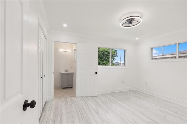 unfurnished bedroom with light hardwood / wood-style floors, ensuite bath, crown molding, and sink