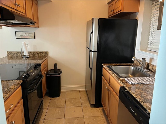 kitchen with appliances with stainless steel finishes, sink, light tile floors, and dark stone counters