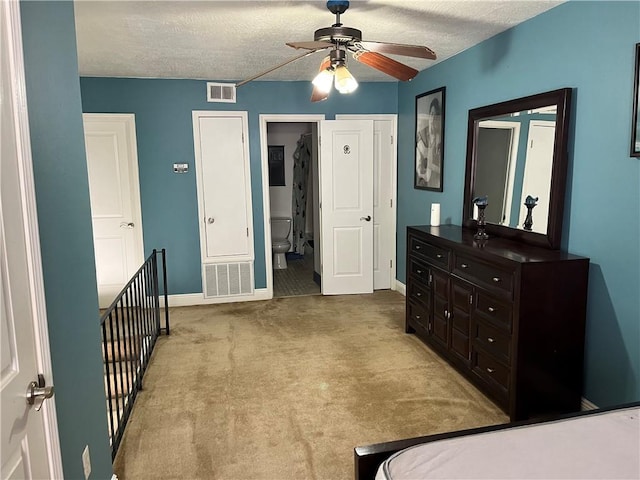 bedroom with carpet, ceiling fan, a textured ceiling, and ensuite bath