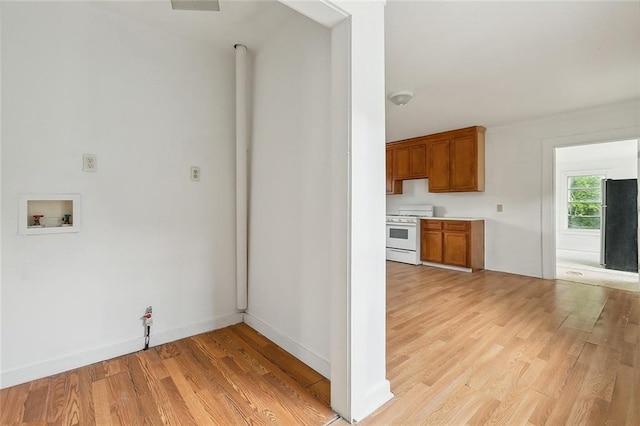 kitchen featuring stainless steel refrigerator, white gas stove, and light wood-type flooring