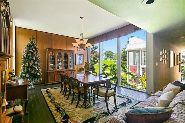 dining area featuring wooden walls and an inviting chandelier