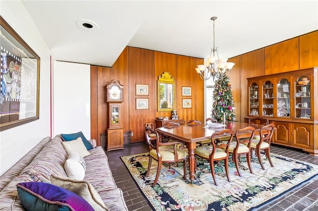 dining area with an inviting chandelier and wood walls