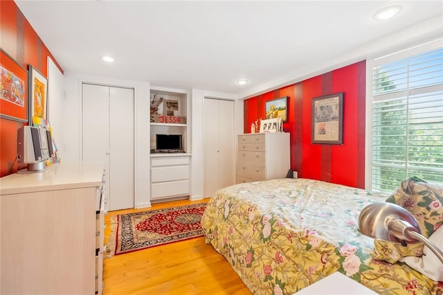 bedroom featuring multiple closets and light wood-type flooring