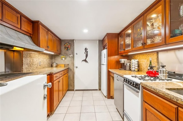 kitchen with light stone counters, white appliances, backsplash, and light tile floors