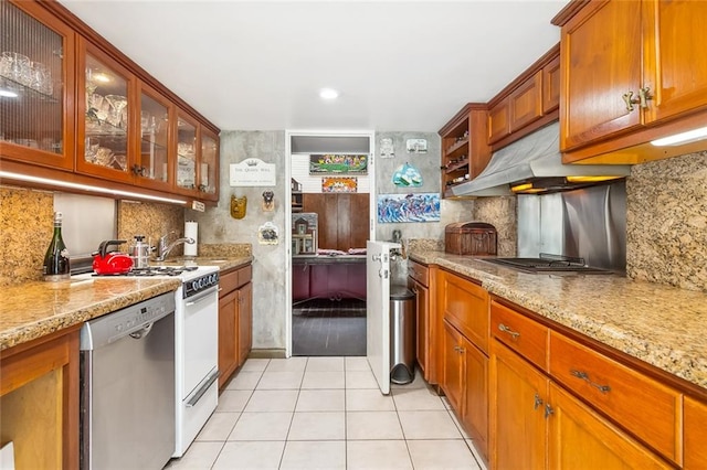 kitchen with appliances with stainless steel finishes, tasteful backsplash, light tile flooring, and light stone counters