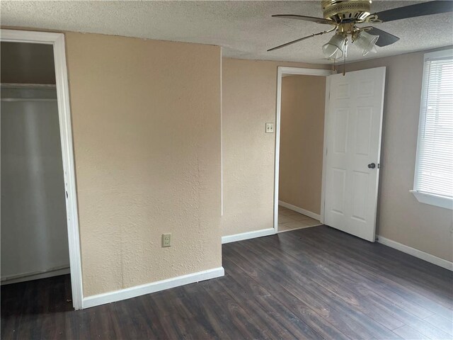 unfurnished bedroom with a textured ceiling, dark wood-type flooring, a closet, and ceiling fan