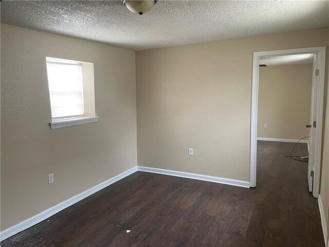 spare room with a textured ceiling and dark wood-type flooring