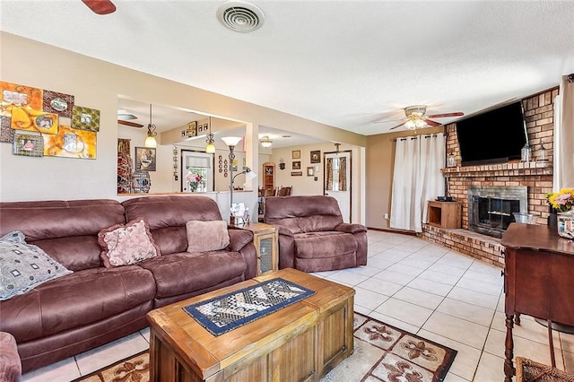 tiled living room with brick wall, a brick fireplace, ceiling fan, and a textured ceiling