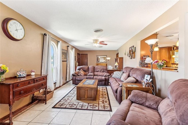 living room with light tile patterned floors, visible vents, a textured ceiling, and ceiling fan
