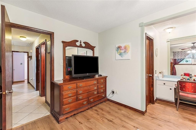 hallway with light wood-type flooring, baseboards, and a textured ceiling
