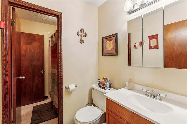 bathroom featuring tile patterned floors, a textured ceiling, toilet, and vanity