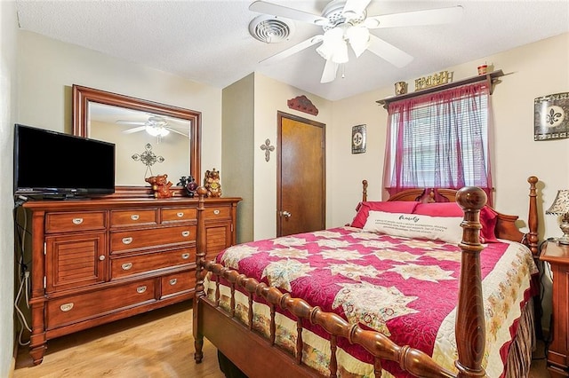 bedroom featuring visible vents, light wood-style floors, a ceiling fan, and a textured ceiling