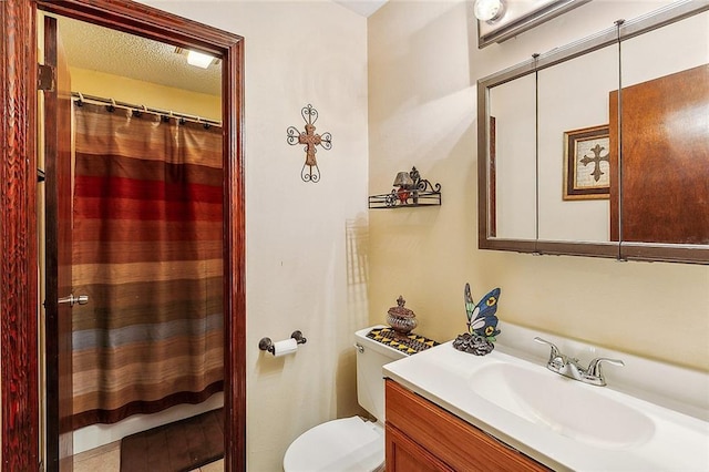 bathroom with vanity, a shower with shower curtain, toilet, and a textured ceiling