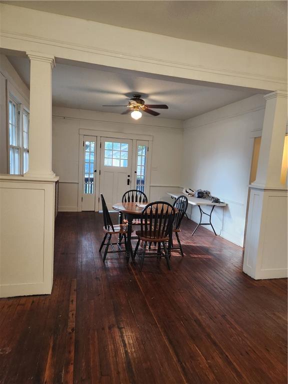 dining space featuring ornate columns, dark wood-style flooring, and ceiling fan