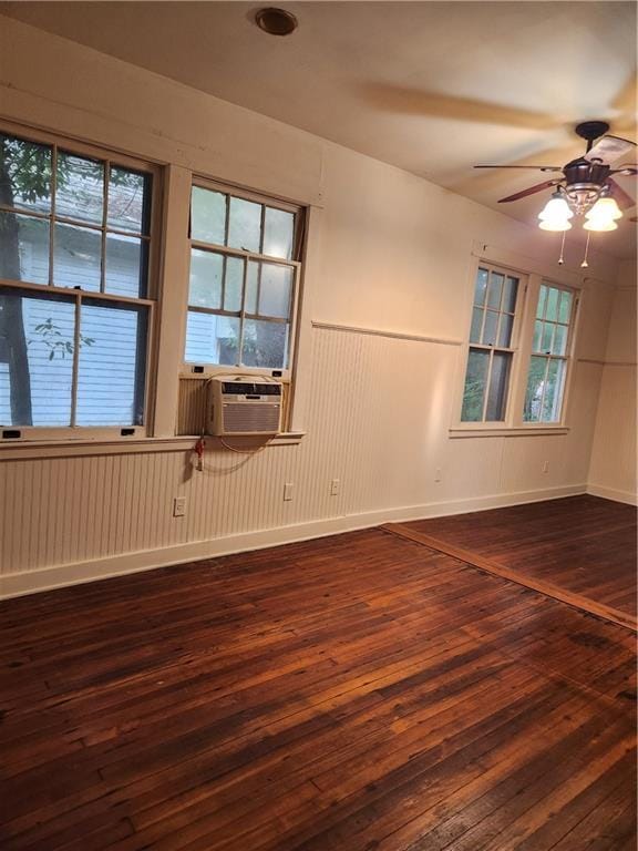 spare room with baseboards, ceiling fan, wood-type flooring, and cooling unit